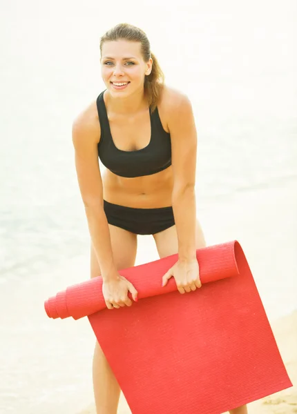 Beautiful woman with a mat after exercise — Stock Photo, Image