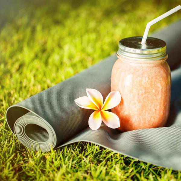 果汁和瑜伽垫在草地上 — 图库照片