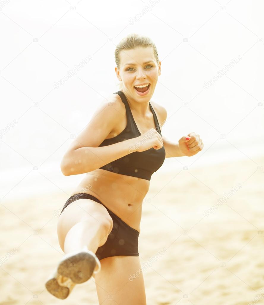 Beautiful woman is doing exercises on the shore