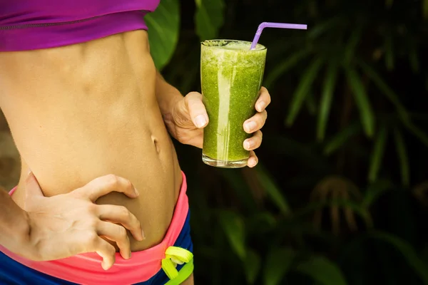 Athletic girl holding a green smoothie — Stock Photo, Image