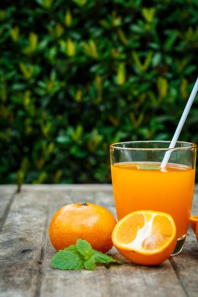 Succo d'arancia con limone, lime e menta su una tavola di legno — Foto Stock