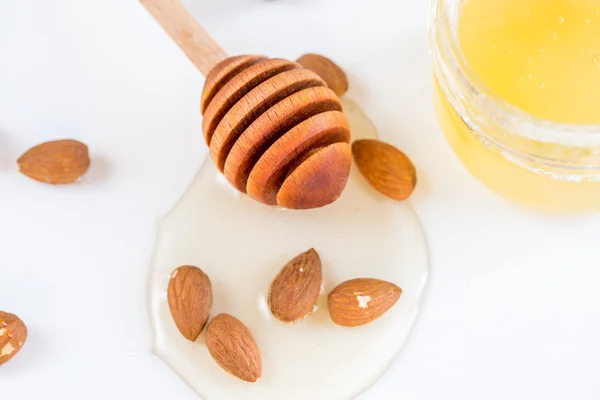 Nueces de almendras con miel sobre blanco. Componente en la cocina —  Fotos de Stock