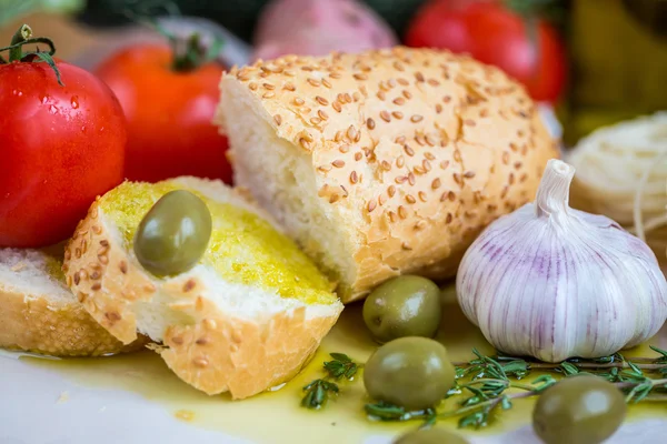 Natives Olivenöl extra auf weißem Baguette und Gemüse — Stockfoto