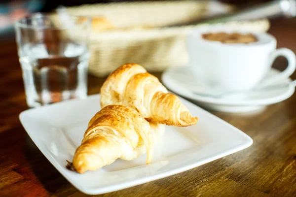 Cappuccino and croissant with water — Stockfoto