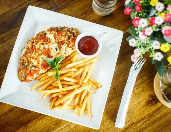 Scrambled eggs and french fries on a wooden table — 스톡 사진