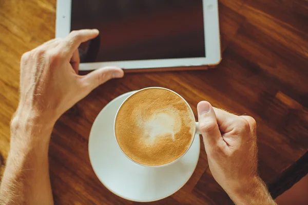 Men's hands hold the tablet with coffee — Stock Photo, Image