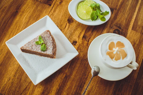 Schokoladenkuchen mit Cappuccino auf einem Holztisch in einem Restaurant — Stockfoto