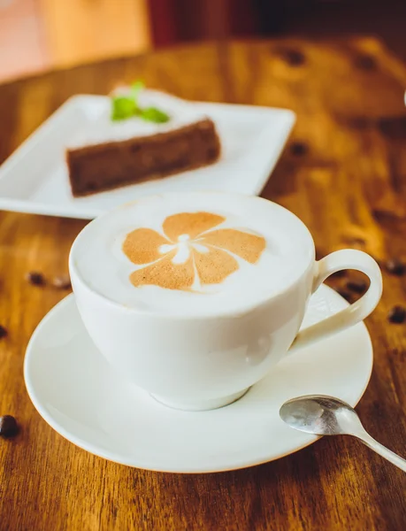 Schokoladenkuchen mit Cappuccino auf einem Holztisch in einem Restaurant — Stockfoto