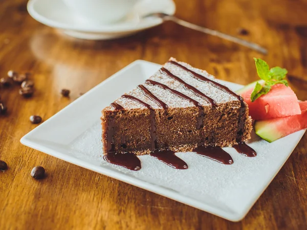 Gâteau au chocolat avec un cappuccino sur une table en bois dans un restaurant — Photo