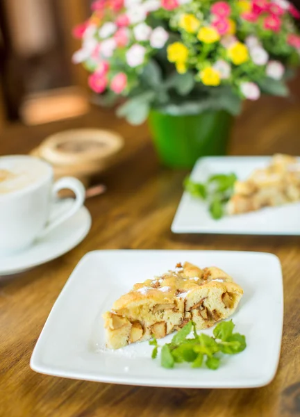 Jablečný koláč a cappuccino na dřevěný stůl — Stock fotografie