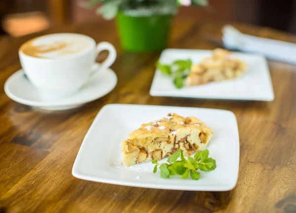 Torta de maçã e cappuccino em uma mesa de madeira — Fotografia de Stock