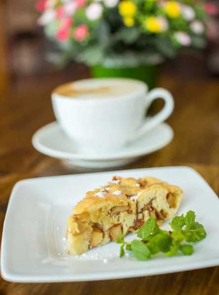 Jablečný koláč a cappuccino na dřevěný stůl — Stock fotografie