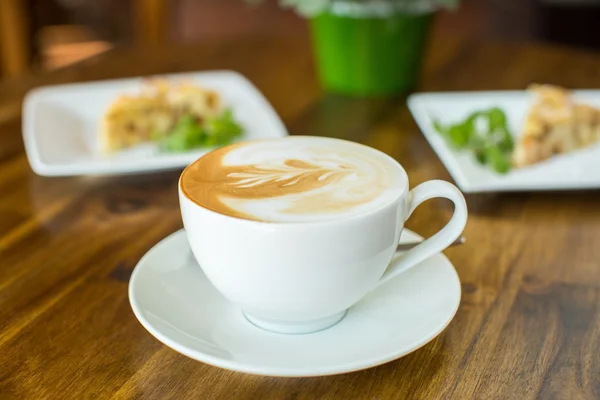 Torta de maçã e cappuccino em uma mesa de madeira — Fotografia de Stock