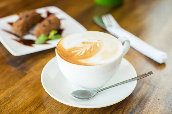 Chocolate cake kartoshka and cappuccino on a wooden table — Stock Photo, Image