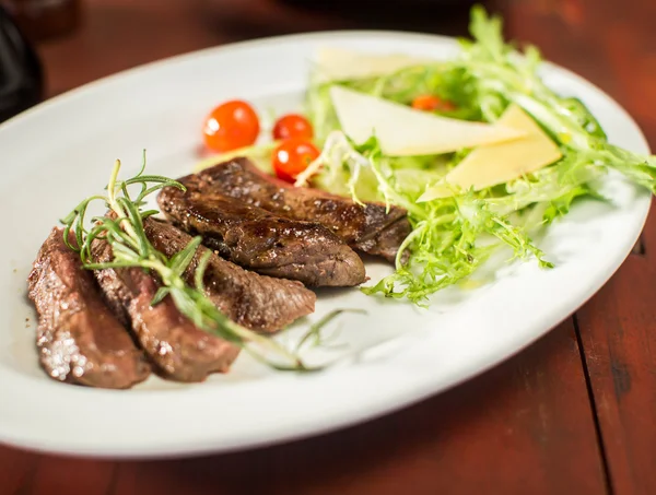 Steak with cheese and vegetables in a restaurant — Stock Photo, Image