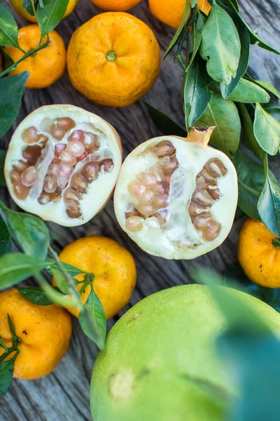 Pomelo, romã e tangerina em uma mesa de madeira — Fotografia de Stock