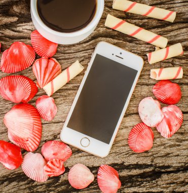 Telefon, kahve, bisküvi ve kabukları ahşap tahta üzerinde