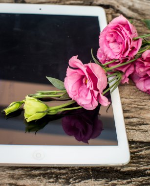 Bir tablet bilgisayar zekâ ile ahşap bir masaya çiçek buketi