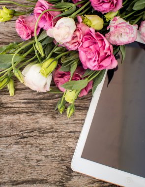 Bir tablet bilgisayar zekâ ile ahşap bir masaya çiçek buketi