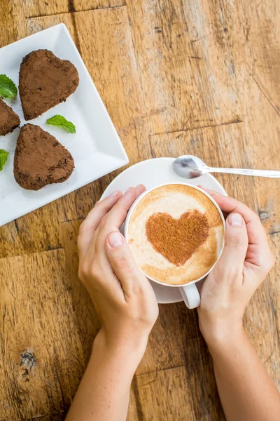 Donna con in mano una tazza di caffè caldo, a forma di cuore e cioccolato — Foto Stock