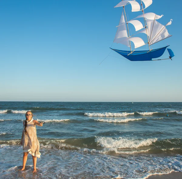 Woman starts a kite on the sea — Stock Photo, Image