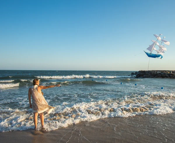 Woman starts a kite on the sea — Stock Photo, Image