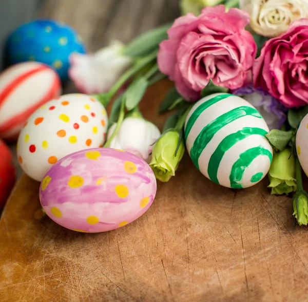 Uova di Pasqua colorate e lisianthus sul tavolo di legno — Foto Stock