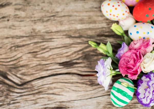 Uova di Pasqua colorate e lisianthus sul tavolo di legno — Foto Stock