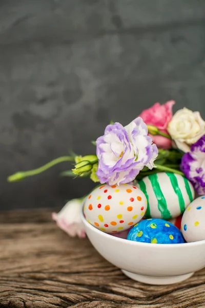 Uova di Pasqua colorate e lisianthus sul tavolo di legno — Foto Stock
