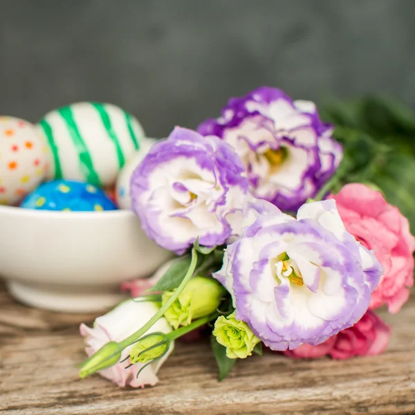 Πολύχρωμα Πασχαλινά αυγά και το lisianthus στο ξύλινο τραπέζι — Φωτογραφία Αρχείου