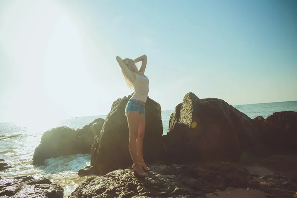 Hermosa mujer rubia en pantalones cortos y camiseta en el mar . — Foto de Stock