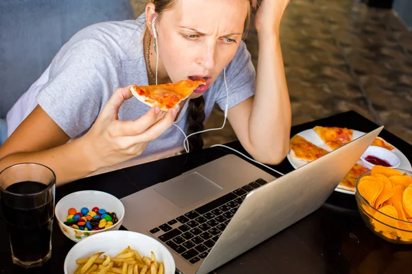 Woman works at the computer and eating fast food. Unhealthy Life