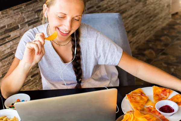 Una donna lavora al computer e mangia fast food. Vita malsana — Foto Stock