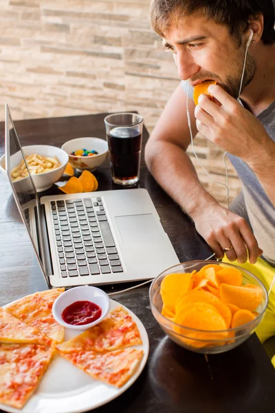 Um homem a trabalhar no computador e a comer fast food. Vida não saudável — Fotografia de Stock