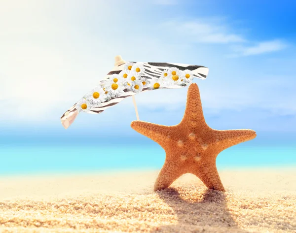 Yaz plaj. Deniz yıldızı ve bir sahil kumu şemsiyesi Stok Resim
