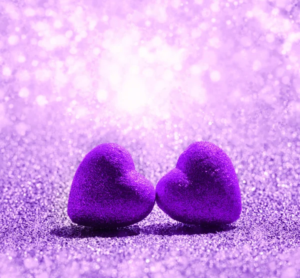 Due cuori viola su sfondo glitter luce astratta — Foto Stock