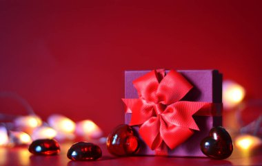 Sevgililer Günü afişi, el yapımı hediye kutusu, fiyonk ve kırmızı arka planda mesaj için yeri olan bir sürü kalp.