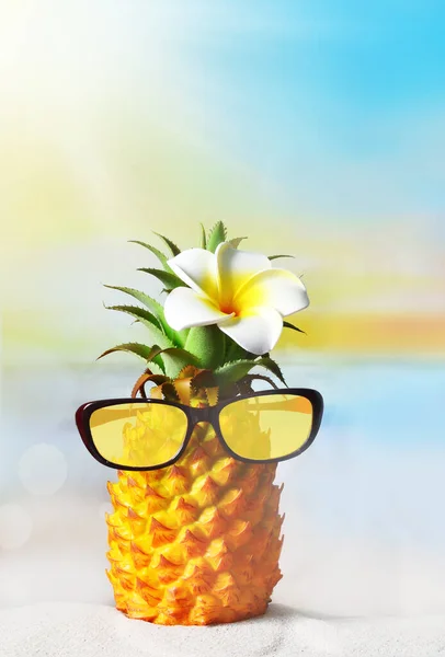 Pineapple with flower and sunglasses in the beach. Summer beach concept.