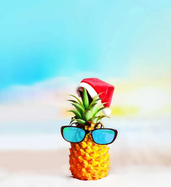 迷人的菠萝与时尚的镜面太阳镜在沙滩上 与海水相映成趣 戴着圣诞帽 热带海滩上的圣诞及新年概念 — 图库照片