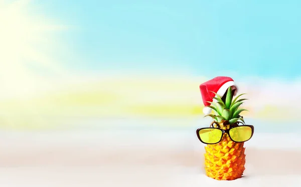 迷人的菠萝与时尚的镜面太阳镜在沙滩上 与海水相映成趣 戴着圣诞帽 热带海滩上的圣诞及新年概念 — 图库照片