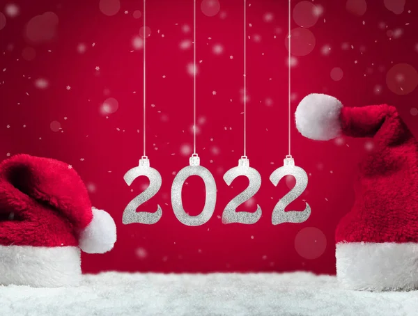 赤い背景に雪の上の2つのサンタの帽子 クリスマスの装飾 休日の概念 2022年 — ストック写真