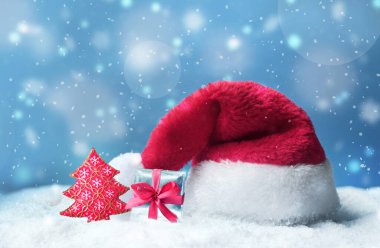 Kar ve mavi kar yağışı arka planlı Noel Baba şapkası.