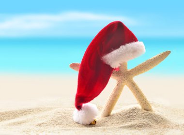 Deniz-yildizli oteller deniz kumlu plaja yürüme Noel Baba şapkası.