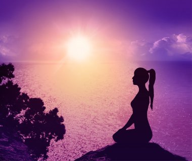 Sahilde bir kadınla silüeti. Yoga ve meditasyon.