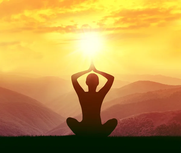 Silueta de una mujer practicando yoga en las montañas — Foto de Stock