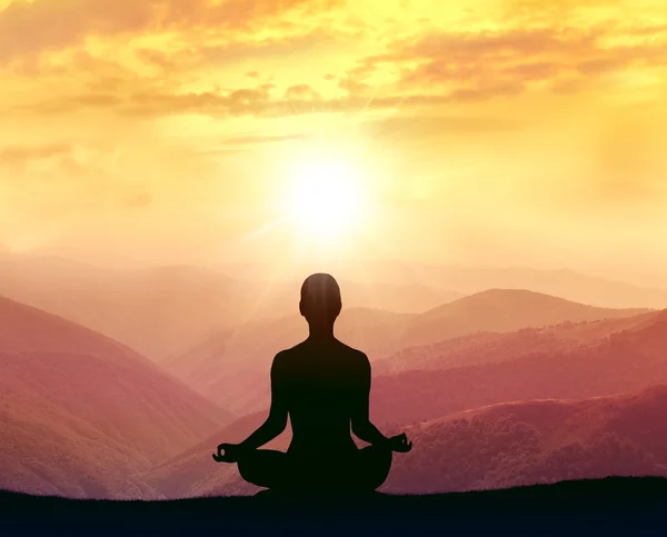 Silueta de una mujer practicando yoga en las montañas — Foto de Stock