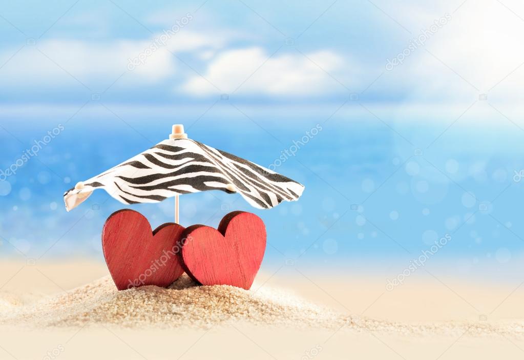 Two hearts under umbrella on the beach. Valentines day.