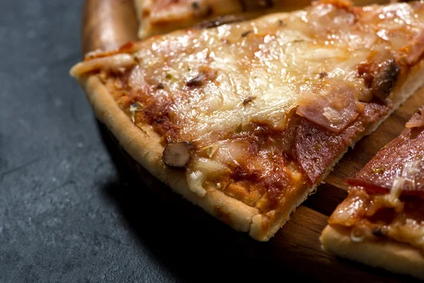 Pizza z serem i kiełbasą na ciemnym tle, zbliżenie — Zdjęcie stockowe