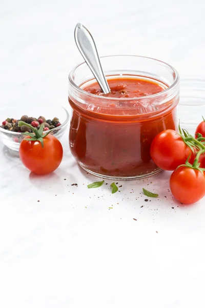 Tomatová omáčka, skleněné nádoby a bílé pozadí, vertikální — Stock fotografie