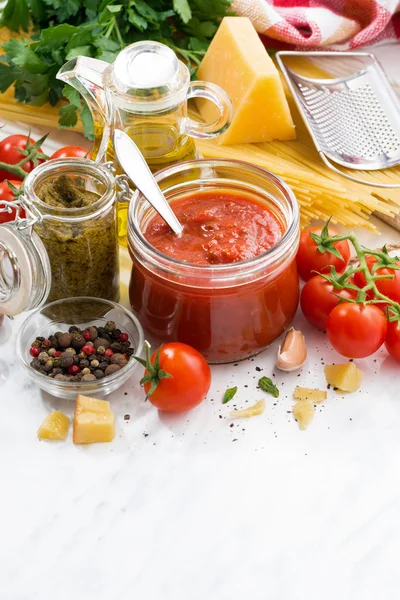 Molho de tomate, pesto e ingredientes para massas em uma mesa branca — Fotografia de Stock